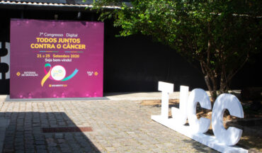 imagem de uma foto externa do 7º Congresso do TJCC, em que a parece um suporte de acrílico com as iniciais, TJCC, e próximo ao objeto um mural que identifica o evento
