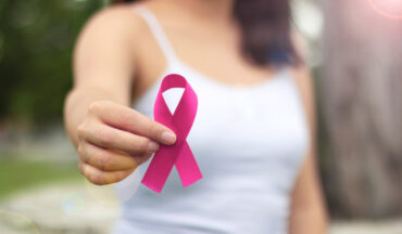 Imagem De Uma Mulher Não Identificada Com O Braço Direito à Frente, Segurando O Laço Da Cor Da Campanha Outubro Rosa Sobre Câncer De Mama