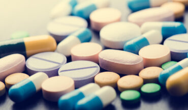 A imagem contém fotos de remédios em vários formatos, a fim de representar a necessidade de medicamentos em Oncologia.