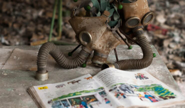 imagem de duas máscaras respiratórias antigas que estão perto de um livro, no qual representa a história do acidente de Chernobyl