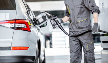 Imagem de um trabalhador em um posto de gasolina prestes a encher o tanque de um carro, em representação aos agentes cancerígenos presentes nesse ambiente de trabalho