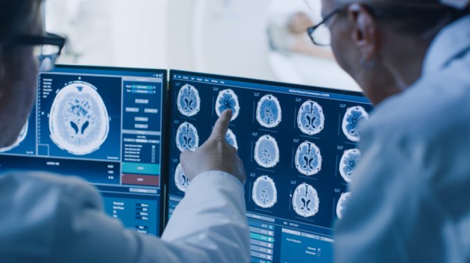 Imagem De Dois Médicos De Costas, Analisando Um Quadro Clínico De Um Paciente, Por Meio De Radiografias Do Cérebro