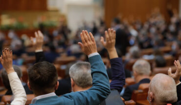 imagem de pessoas de costas sentadas em cadeiras levantando a mão