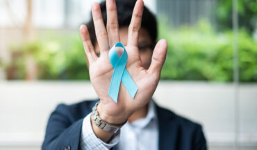 imagem de um homem com o laço da campanha Novembro Azul colado na palma da sua mão