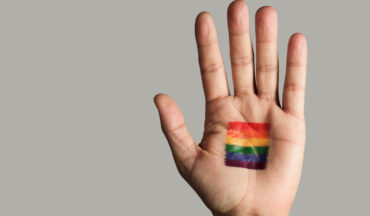 imagem de uma palma da mão pintada de com as cores da bandeira LGBTQIA+