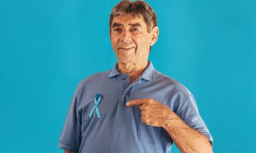 Imagem De Um Homem Idoso Apontando O Dedo Para O Laço Da Campanha Novembro Azul Em Sua Camiseta