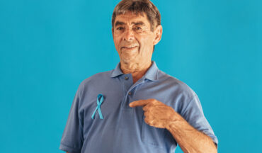 imagem de um homem idoso apontando o dedo para o laço da campanha Novembro Azul em sua camiseta