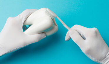 imagem de uma mão segurando uma escova de dentes e outra um objeto em formato de dente