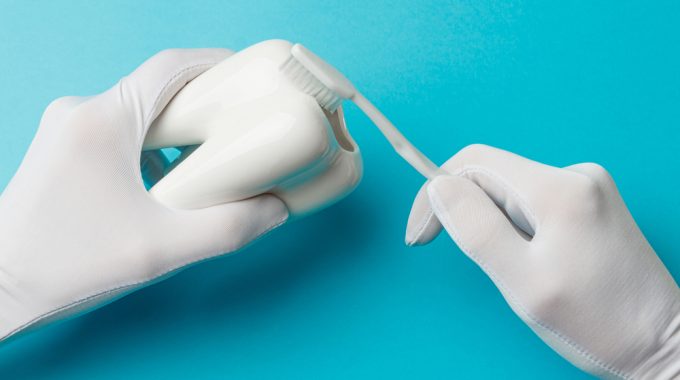 Imagem De Uma Mão Segurando Uma Escova De Dentes E Outra Um Objeto Em Formato De Dente