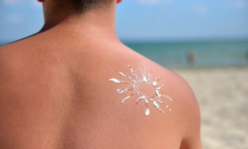 Imagem Das Costas De Um Homem Com Protetor Solar Na Praia