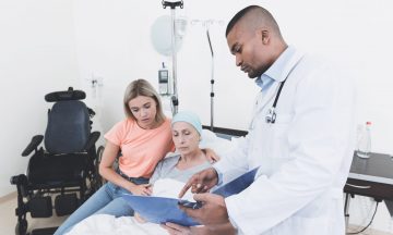 Imagem De Uma Paciente Com Câncer Sendo Abraçada Pelo Seu Familiar E Ao Lado Um Médico Indicando Algum Informação Na Prancheta