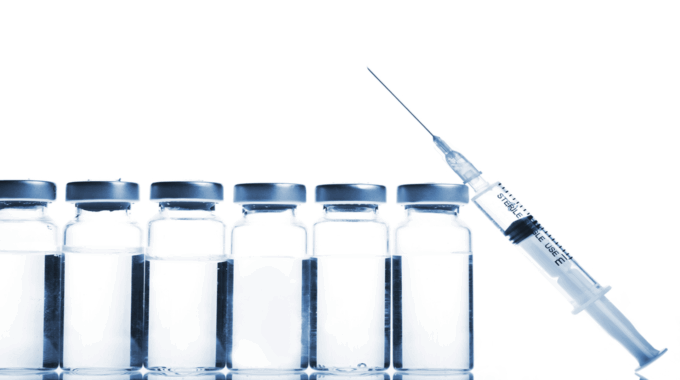 Imagem de quatro ampôlas de medicamento transparente transparente e seringa com agulha.